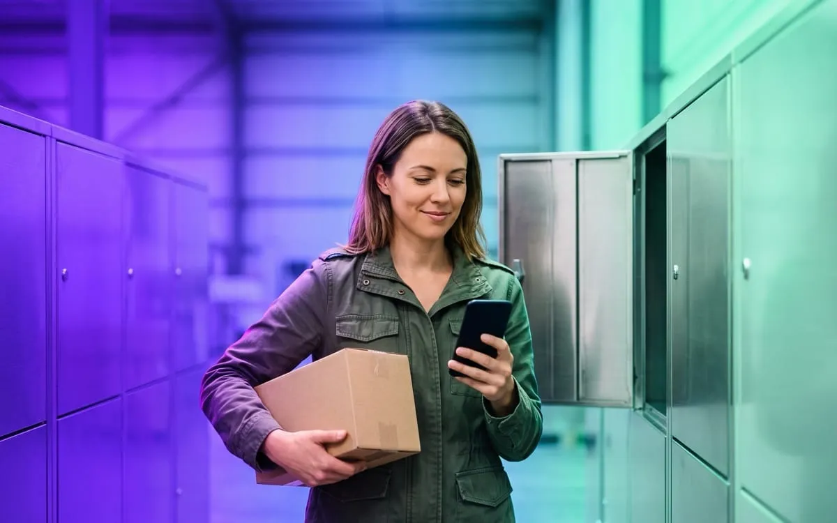 Una cliente ritira il pacco da un locker, con lo smartphone in mano